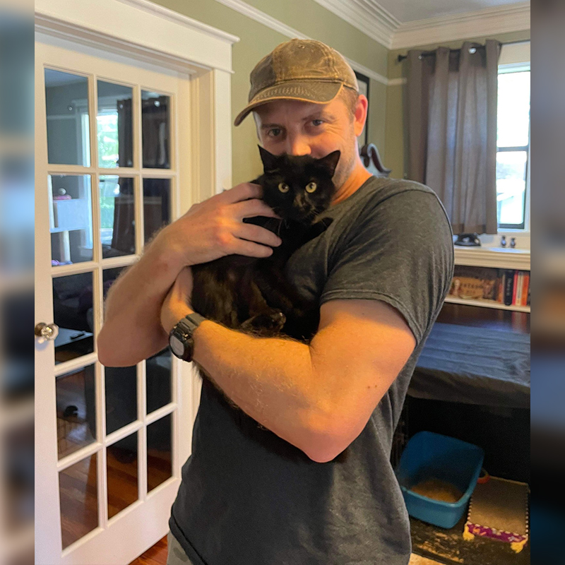 Cat Man Chris with a rescued black cat Miss Moneypenny