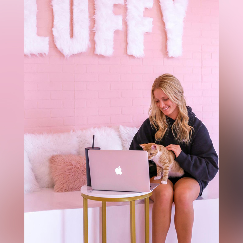 girl works on laptop at Tampa cat café with orange kitten 