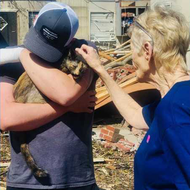 Mason holds Athena the cat as neighbor pets her after deadly tornado in Rolling Fork, MS