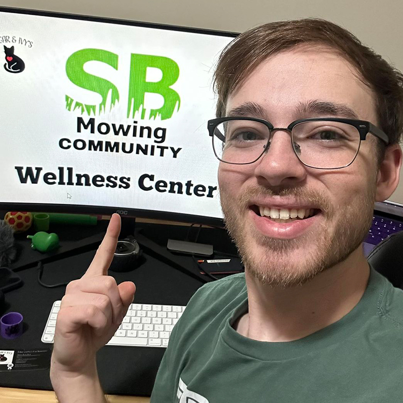 Spencer, Corpus Christi, Texas, Anissa Beal, Edgard and Ivy's Cat Sanctuary, SB Mowing, Esbee the cat, Kansas, Wichita, lawn mower, man mowing lawns for free, cat saved by man mowing lawns from Kansas, Spencer smiles with picture of the wellness center logo